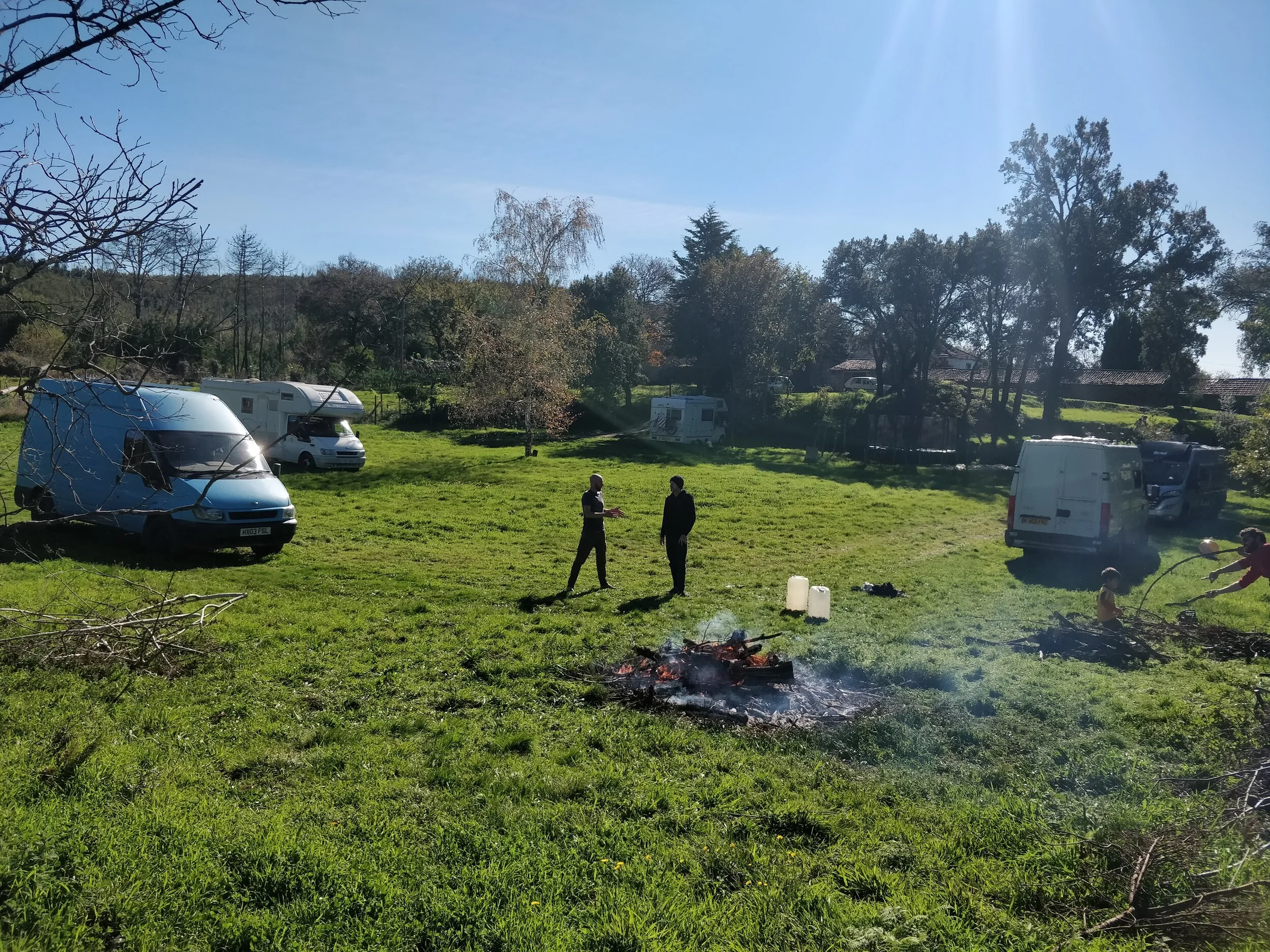 Travellers sharing a campfire beside campervans on one of the camping fields