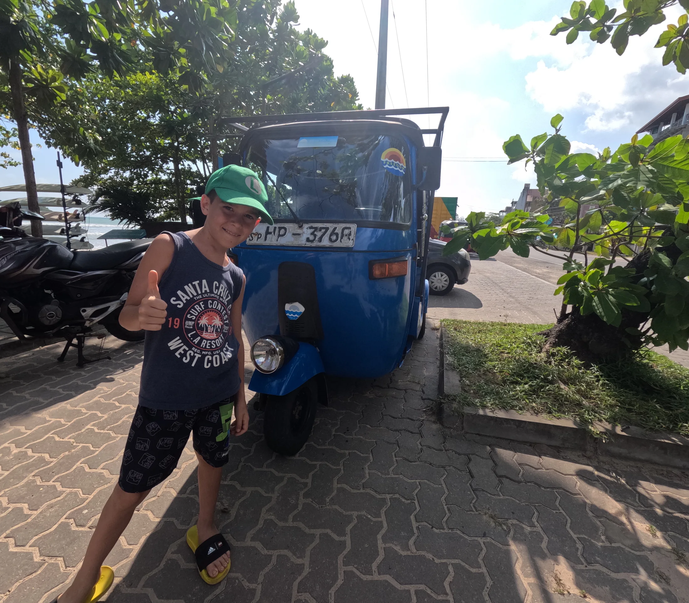 Lawrie standing beside a blue tuk-tuk in Sri Lanka